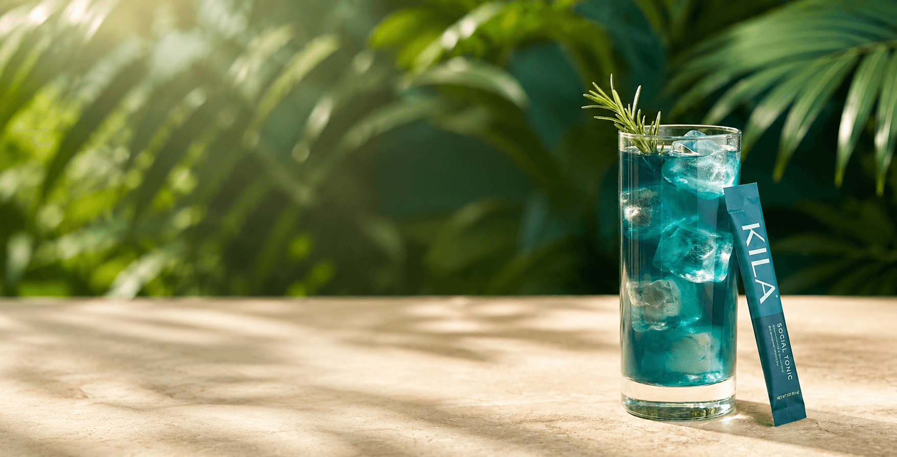 KILA Social Tonic poured over ice with rosemary on a sunlit travertine bar, tropical palms behind